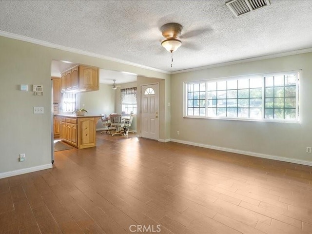 unfurnished living room featuring ornamental molding, a textured ceiling, and hardwood / wood-style flooring