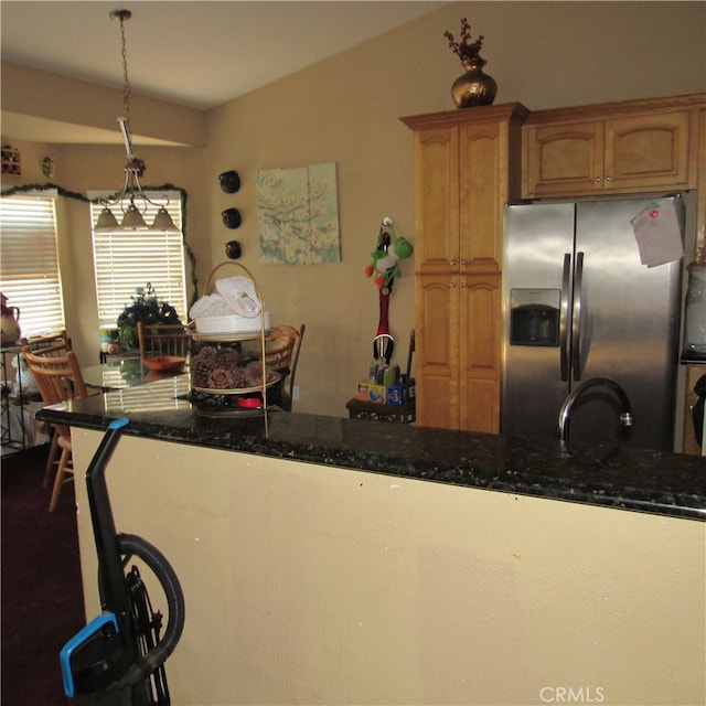 kitchen featuring dark stone countertops, pendant lighting, and stainless steel fridge