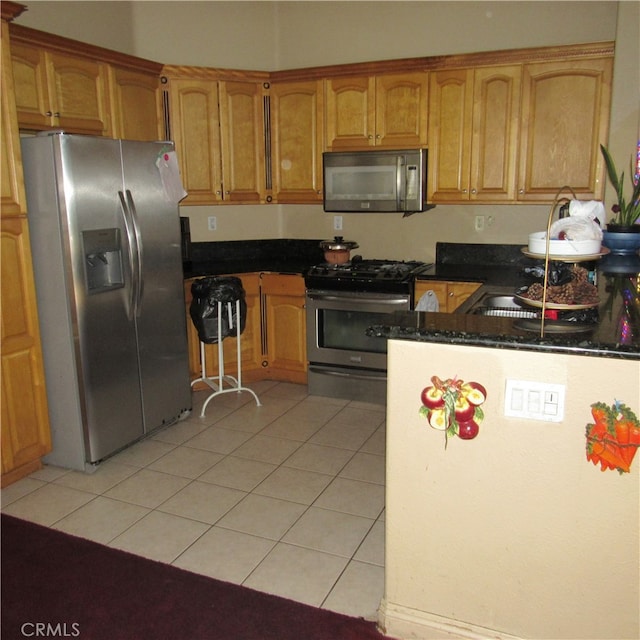 kitchen featuring light tile patterned flooring, appliances with stainless steel finishes, sink, and dark stone counters