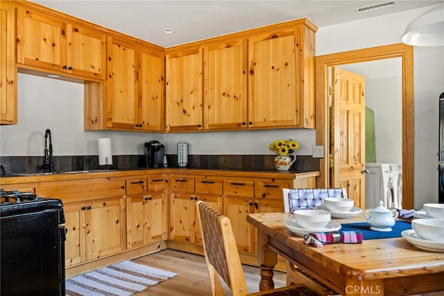 kitchen featuring light hardwood / wood-style floors, black range, sink, and separate washer and dryer