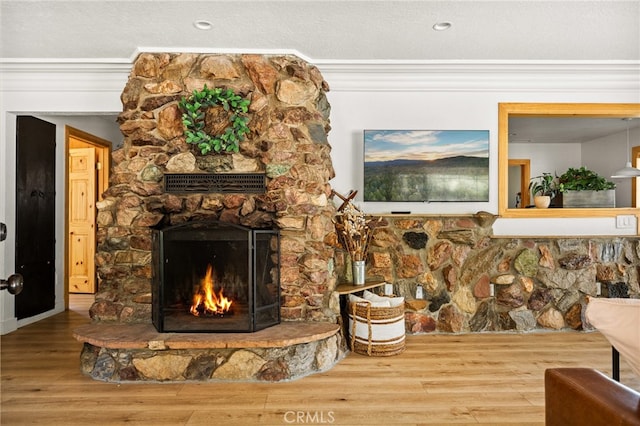 interior space with a stone fireplace, crown molding, hardwood / wood-style floors, and a textured ceiling