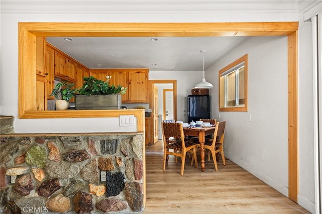 kitchen with pendant lighting, light wood-type flooring, and black refrigerator