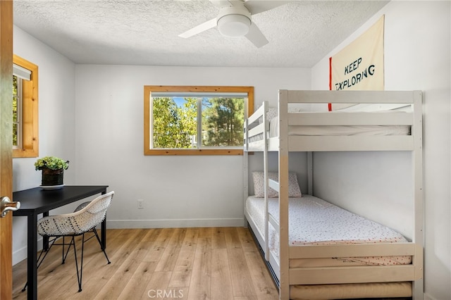 bedroom with a textured ceiling, light wood-type flooring, and ceiling fan