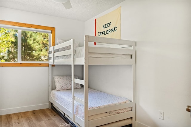 bedroom with a textured ceiling, hardwood / wood-style flooring, and ceiling fan