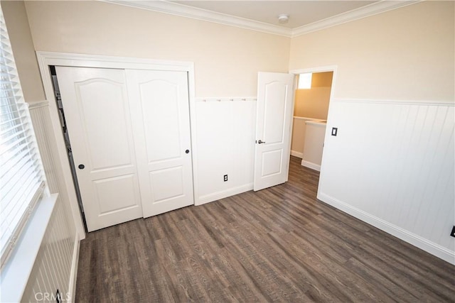 unfurnished bedroom featuring dark hardwood / wood-style floors, crown molding, and a closet