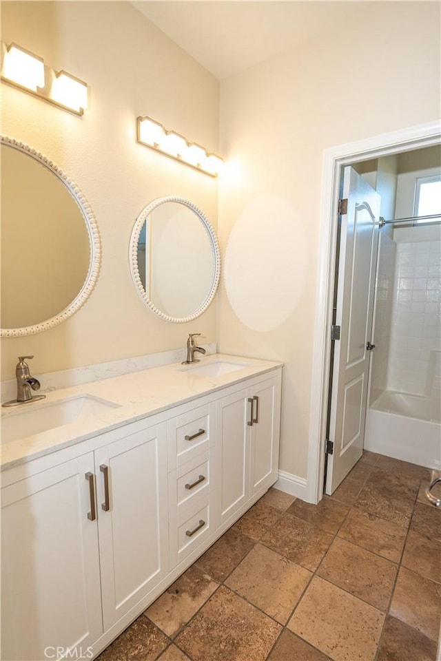 110 Montage Dr, Merced, CA 95348 - bathroom with double vanity, stone tile flooring, baseboards, and bathtub / shower combination