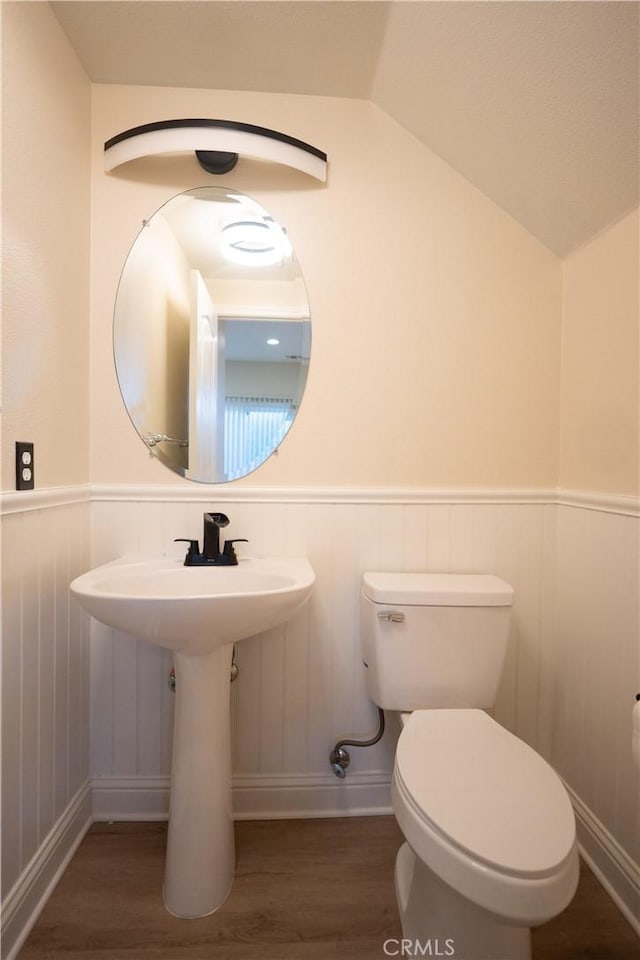 bathroom featuring toilet, wood-type flooring, and vaulted ceiling