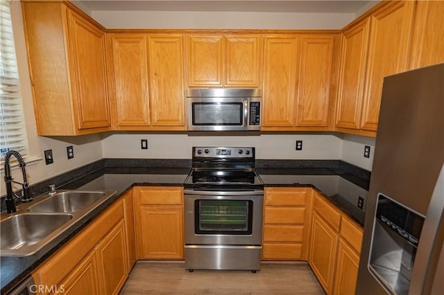110 Montage Dr, Merced, CA 95348 - kitchen featuring appliances with stainless steel finishes, a sink, light wood-type flooring, and dark countertops