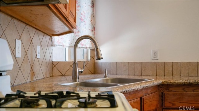 kitchen featuring ventilation hood, light countertops, a sink, and brown cabinets