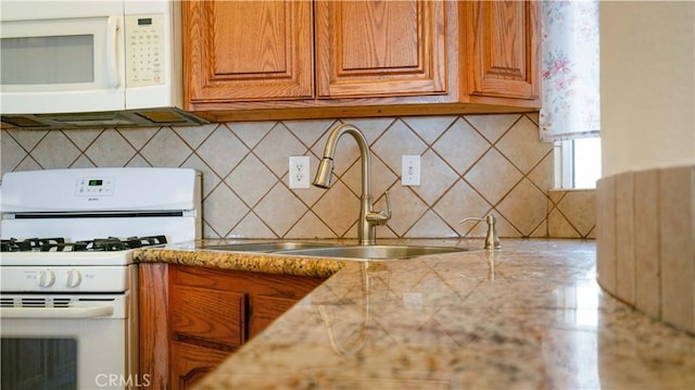 kitchen with brown cabinetry, light countertops, white appliances, and a sink