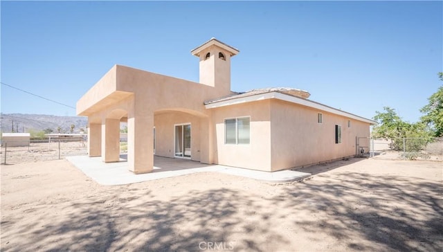 back of house featuring stucco siding, fence, a patio, and a mountain view