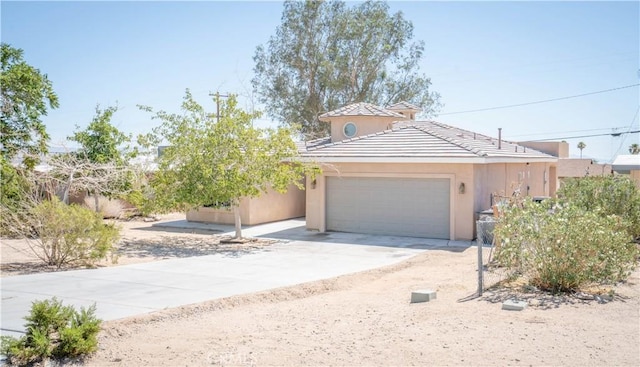 view of front of property featuring an attached garage, a tiled roof, stucco siding, and concrete driveway