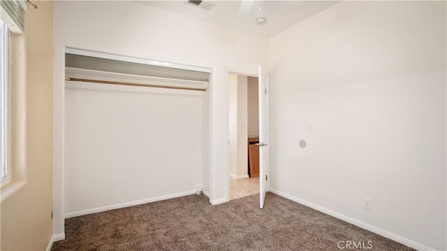 unfurnished bedroom featuring baseboards, carpet floors, and a closet