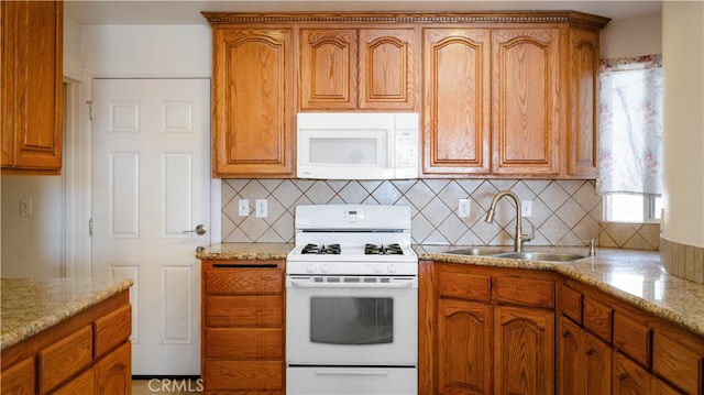 kitchen featuring light stone countertops, white appliances, sink, and tasteful backsplash