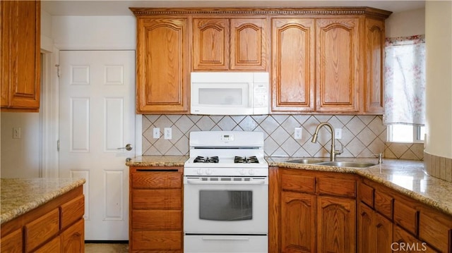 kitchen with decorative backsplash, white appliances, a sink, and brown cabinetry