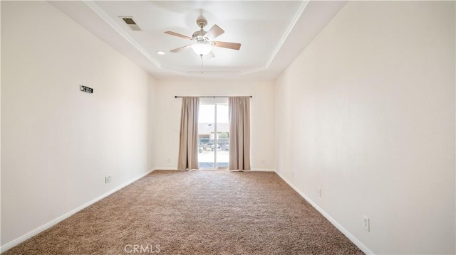 carpeted spare room featuring ceiling fan, baseboards, visible vents, and a raised ceiling