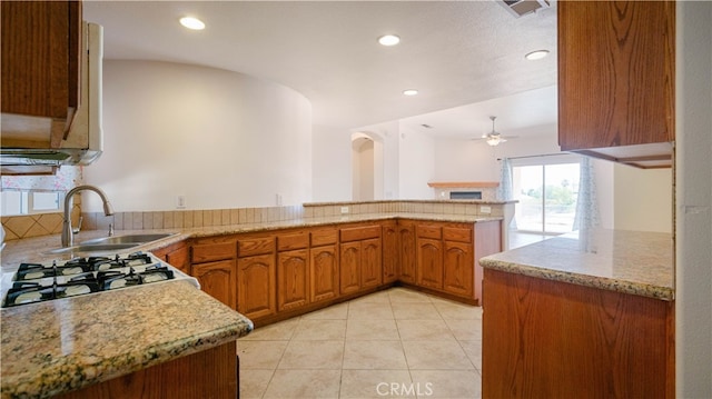 kitchen featuring kitchen peninsula, light stone countertops, ceiling fan, sink, and light tile patterned floors