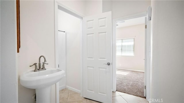 bathroom featuring tile patterned flooring, baseboards, and a sink