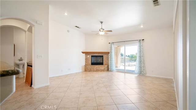 unfurnished living room with a fireplace, ceiling fan, and light tile patterned flooring