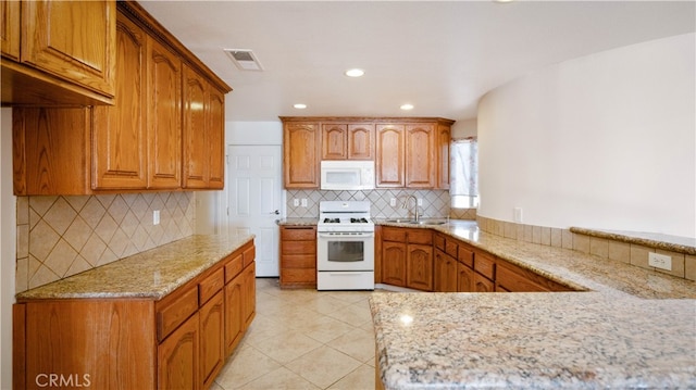 kitchen with white appliances, sink, light stone countertops, tasteful backsplash, and kitchen peninsula