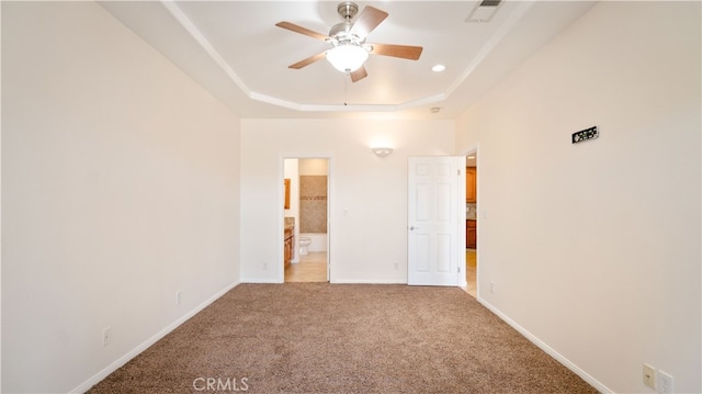 unfurnished bedroom featuring carpet flooring, ceiling fan, connected bathroom, and a tray ceiling