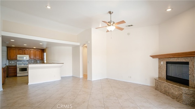 unfurnished living room featuring ceiling fan, light tile patterned floors, and a premium fireplace