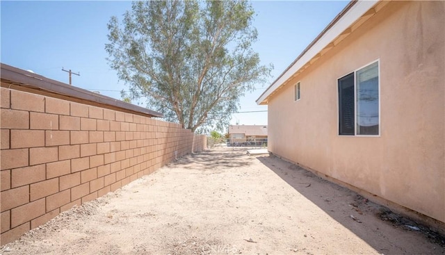 view of side of home with fence and stucco siding