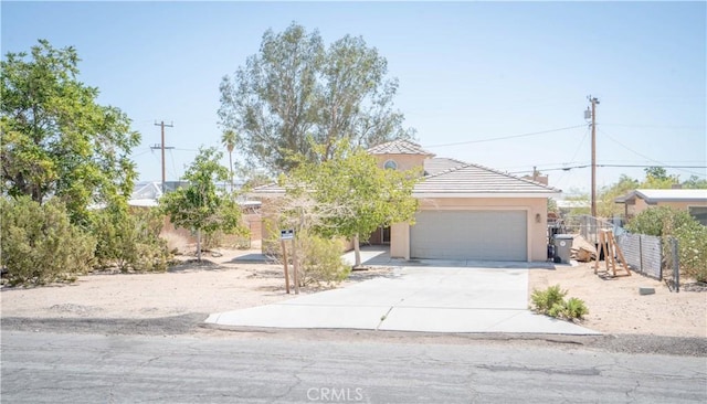 view of front of house with a tiled roof, driveway, fence, a garage, and stucco siding