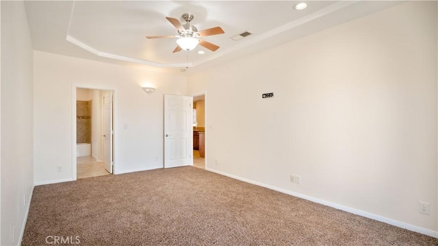 empty room featuring light carpet, baseboards, visible vents, ceiling fan, and a raised ceiling