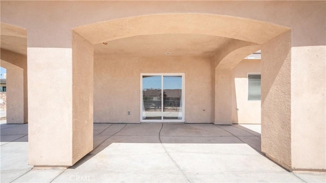 doorway to property with a patio and stucco siding