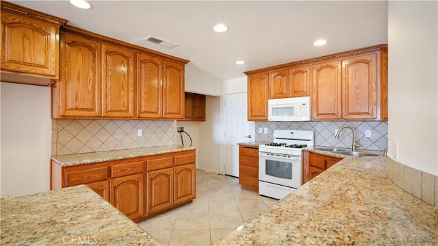 kitchen with light tile patterned floors, white appliances, light stone counters, and sink