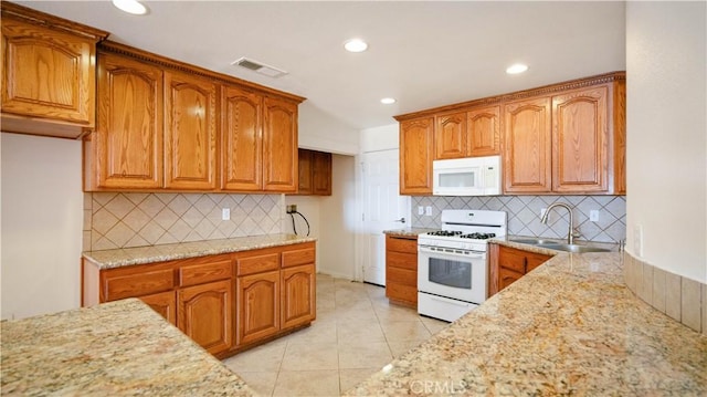 kitchen featuring brown cabinetry, a sink, and white appliances