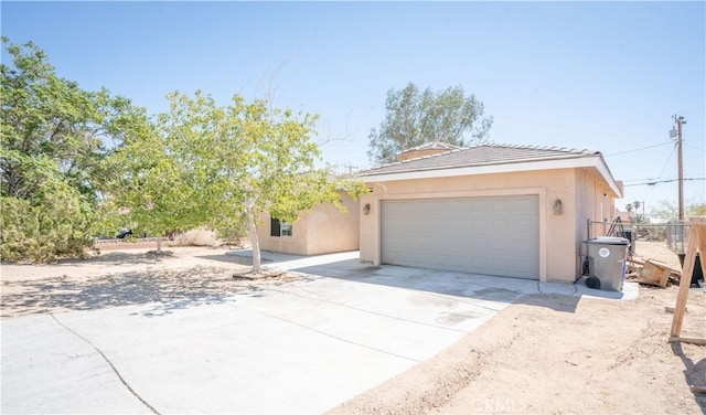 ranch-style house featuring fence, stucco siding, a tile roof, driveway, and a garage