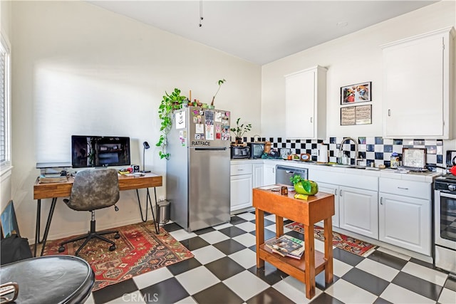 kitchen with white cabinets, appliances with stainless steel finishes, tasteful backsplash, and sink