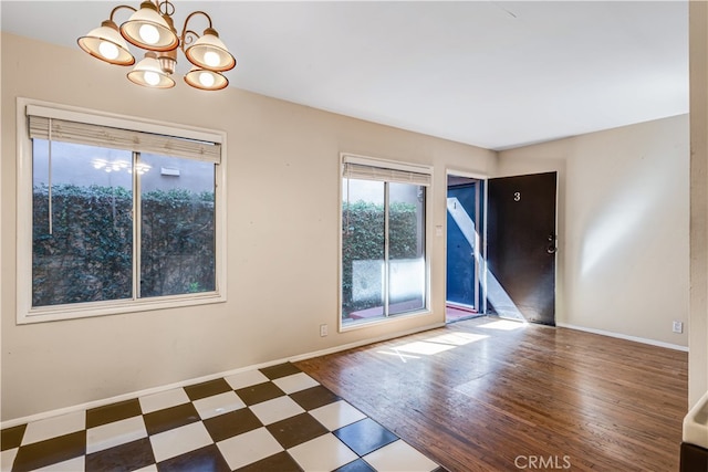 empty room featuring an inviting chandelier and hardwood / wood-style floors