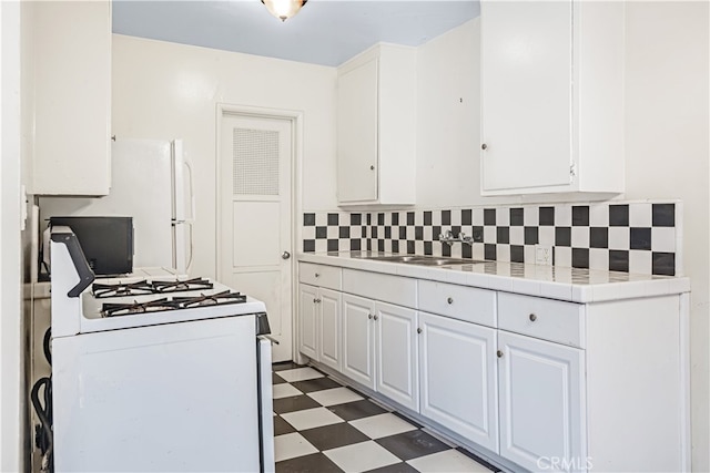 kitchen featuring sink, white cabinetry, decorative backsplash, tile countertops, and white range with gas cooktop