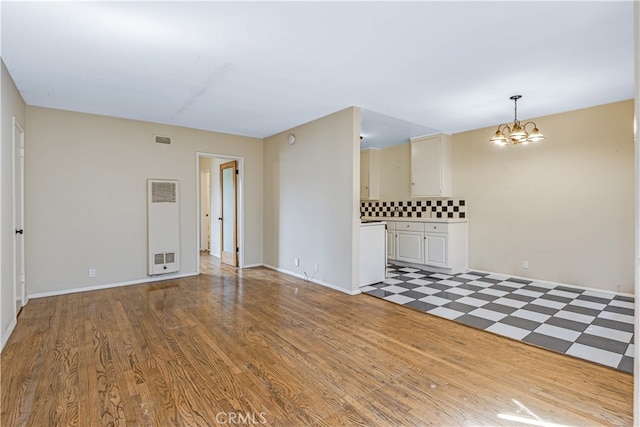 spare room featuring a notable chandelier and light hardwood / wood-style floors