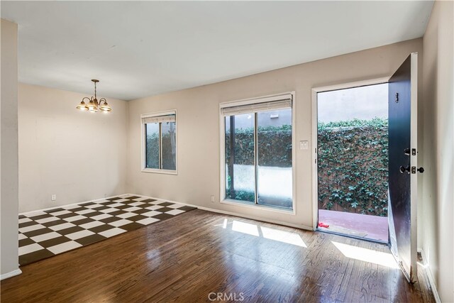 unfurnished room featuring a chandelier and dark hardwood / wood-style floors