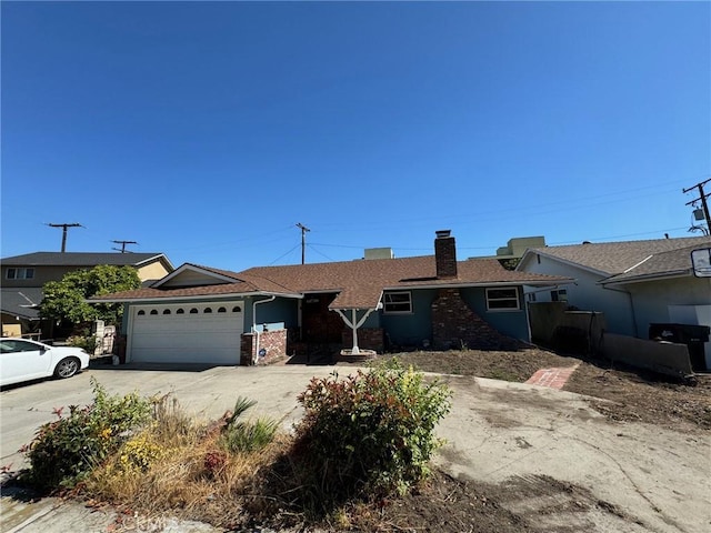 ranch-style house featuring a garage, driveway, and a chimney