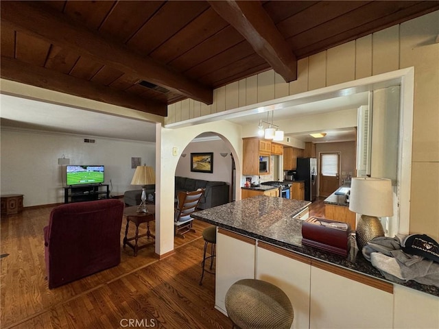 kitchen with dark hardwood / wood-style floors, a breakfast bar, wood ceiling, appliances with stainless steel finishes, and beamed ceiling