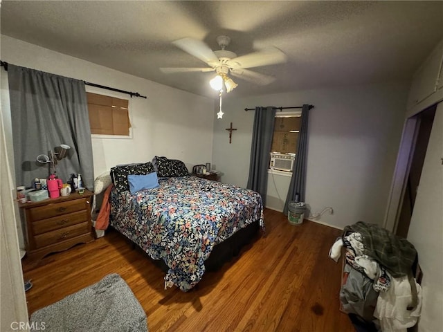 bedroom featuring ceiling fan, hardwood / wood-style floors, cooling unit, and a textured ceiling