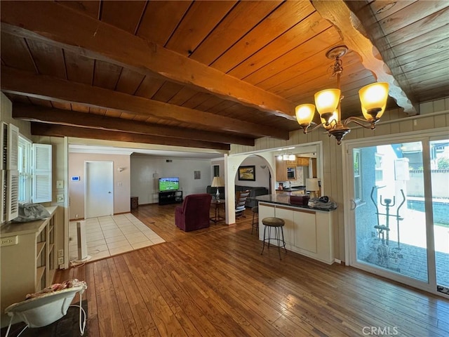 interior space featuring decorative light fixtures, wooden ceiling, hardwood / wood-style flooring, a chandelier, and beam ceiling