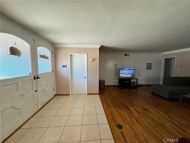 entryway with light wood-type flooring, baseboards, visible vents, and ornamental molding