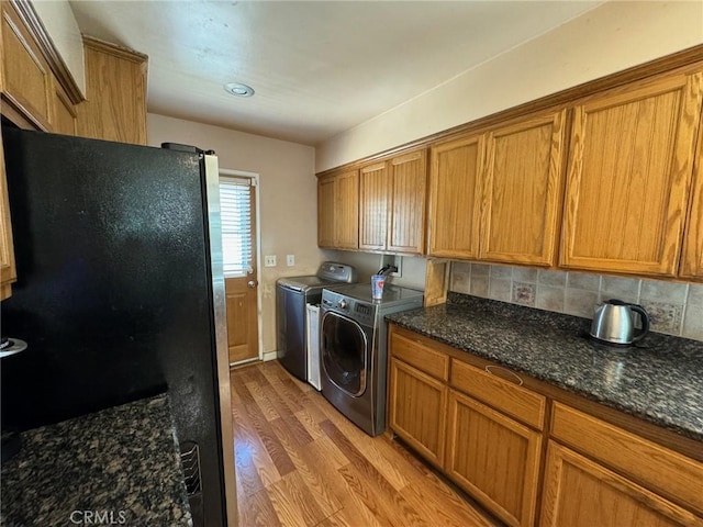 laundry room with washing machine and clothes dryer, cabinets, and light hardwood / wood-style flooring