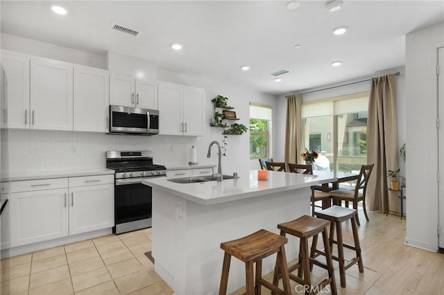 3570 E Peckham Paseo Unit 3, Ontario, CA 91761 - kitchen featuring visible vents, white cabinetry, tasteful backsplash, a sink, and appliances with stainless steel finishes