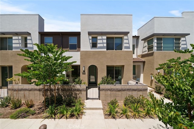 view of front of home with a fenced front yard, a gate, and stucco siding