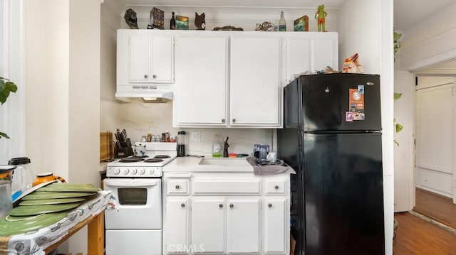 kitchen featuring hardwood / wood-style floors, black refrigerator, white cabinetry, and white range oven