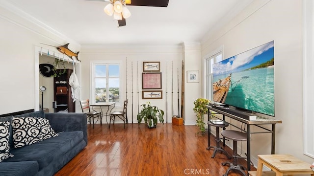 living room with ornamental molding, dark wood-type flooring, and ceiling fan