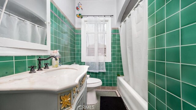 full bathroom with toilet, tile patterned flooring, shower / tub combo, vanity, and tile walls