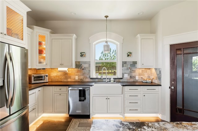 kitchen with appliances with stainless steel finishes, white cabinets, sink, and pendant lighting